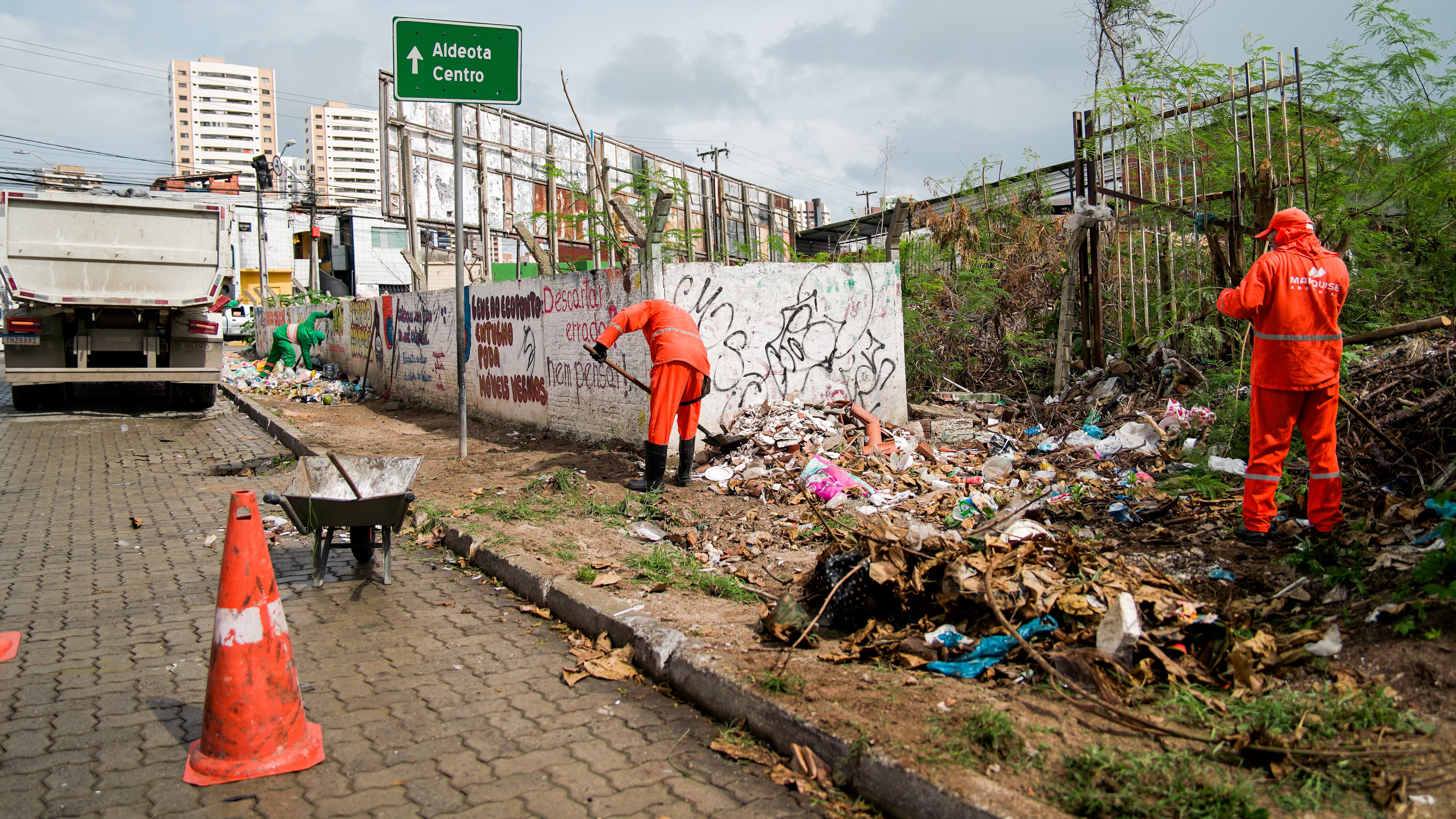 homens recolhendo lixo numa calçada